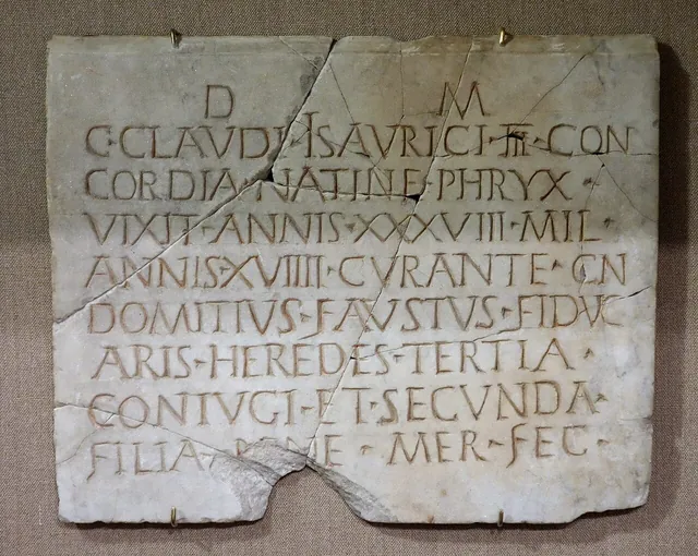 A cracked Roman marble tombstone for Gaius Claudius Isauricus with red-painted letters, including VIXIT ANNIS XXXVIII and ANNIS XVIIII.
